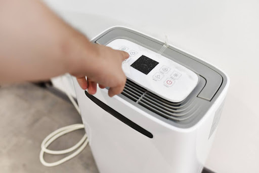 Homeowner pressing button on dehumidifier machine