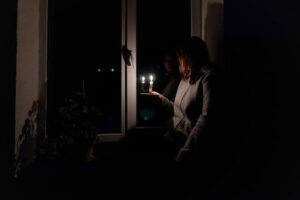 Woman holding light as power outage affects her home.