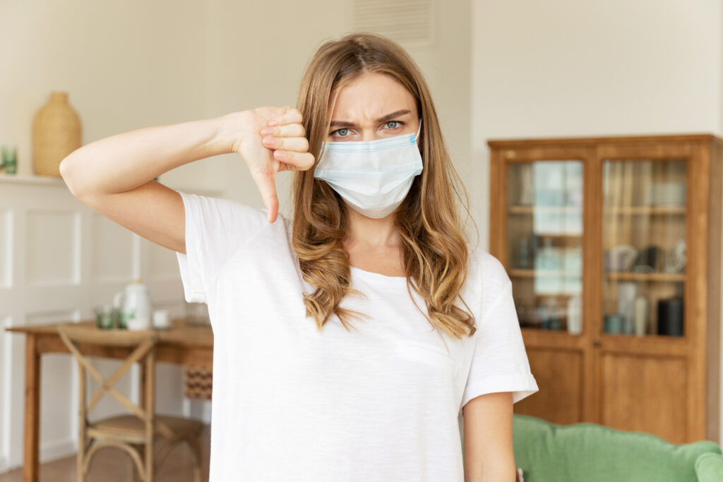 Homeowner wearing mask indoor gives thumbs down to poor indoor air quality.